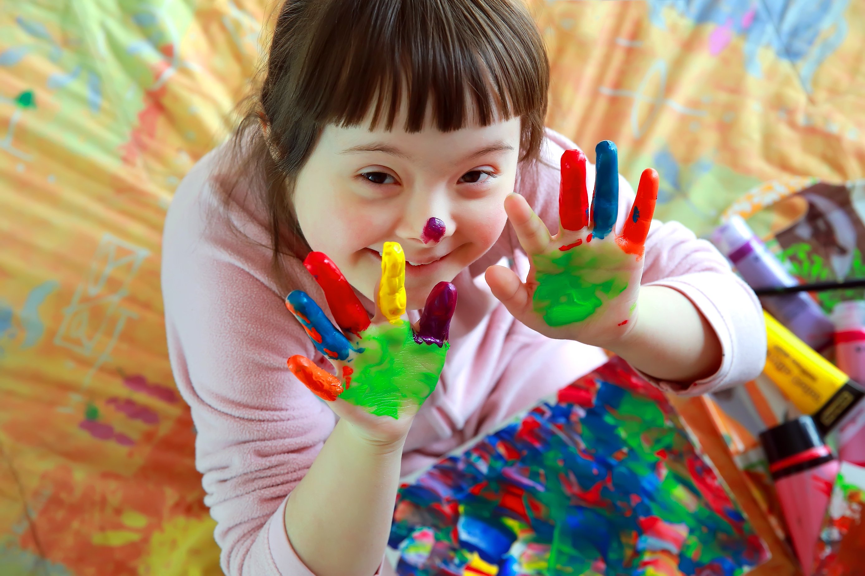 une petite fille avec les mains remplis de peinture est présente sur cette photo