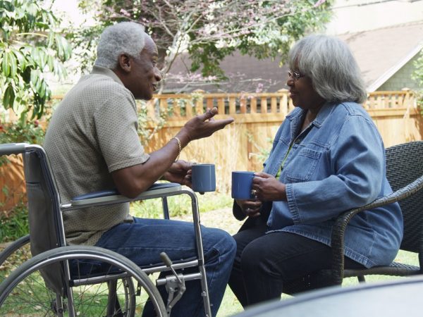 un couple de personnes âgées dont l'homme se trouve en fauteuil roulant et la femme sur une chaise apparait sur la photo