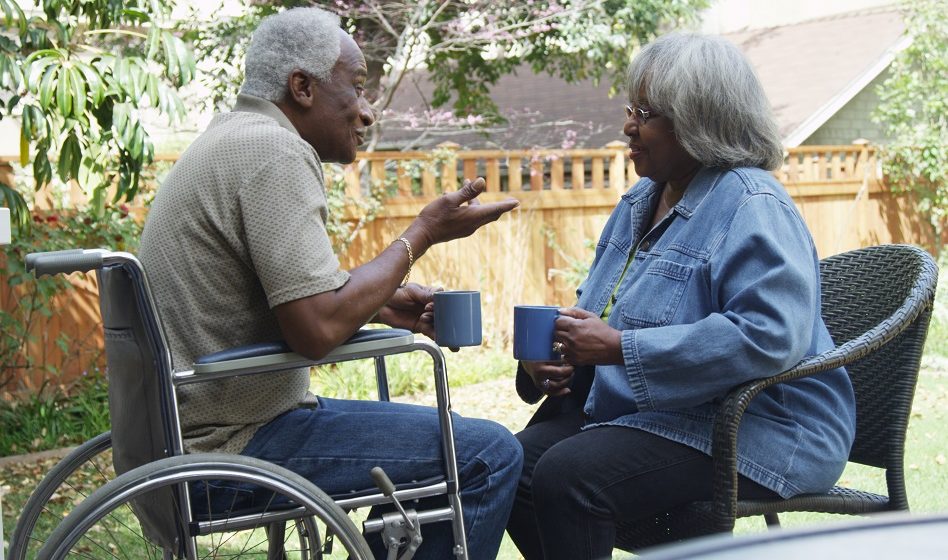 un couple de personnes âgées dont l'homme se trouve en fauteuil roulant et la femme sur une chaise apparait sur la photo